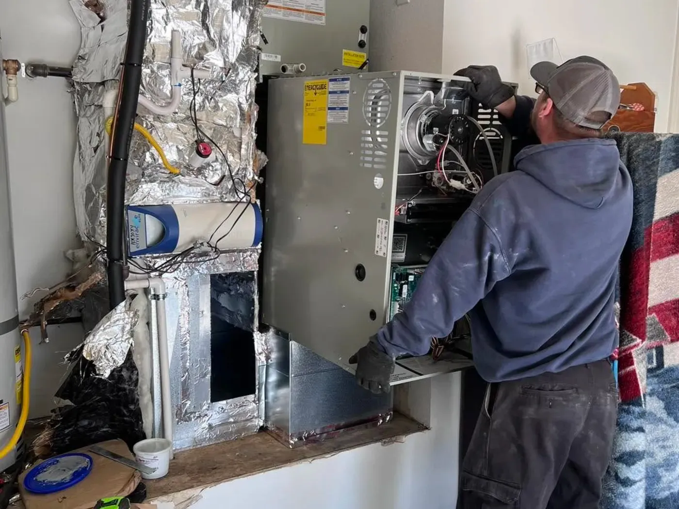 A Dayco technician working on an indoor furnace and duct connection